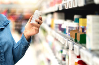 A customer looks at the labels of acetaminophen and ibuprofen.