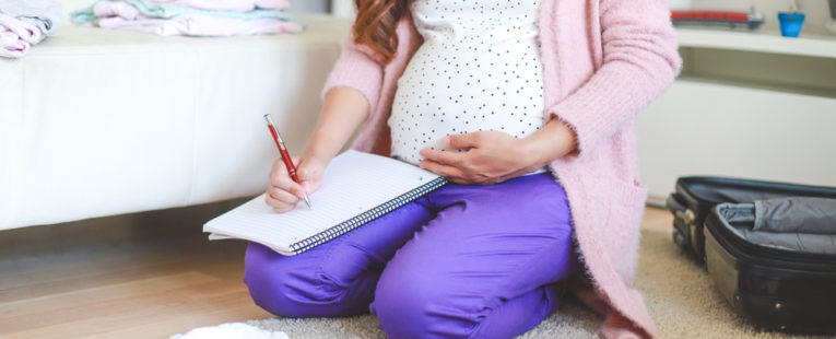 A pregnant woman sits down to write down her birth plan.
