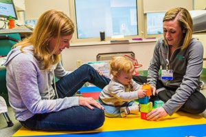 Congenital heart patient toddler playing with mom and therapist. 