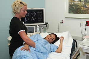 EKG tech performing an echocardiogram on female patient