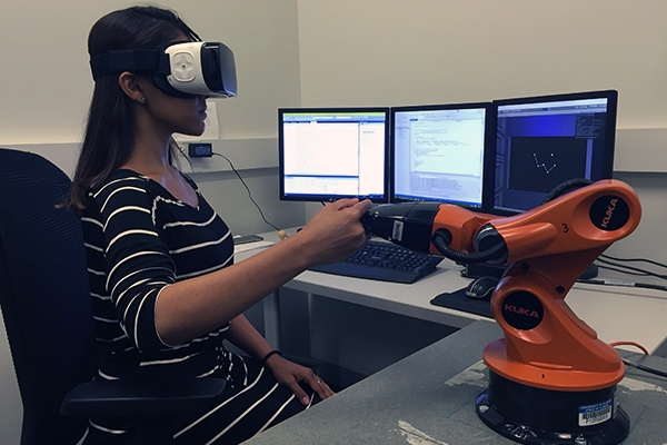 Young woman using virtual reality simulation equipment in a lab setting. 