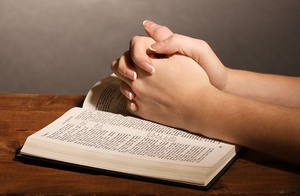 Hands Praying on Bible